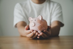 Man holding a piggy bank with a bandage on its side.