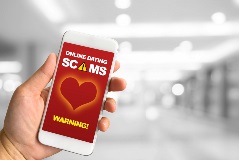 Phone showing online dating scam warning.