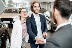 Couple shaking hands in the dealership after a new car purchase.