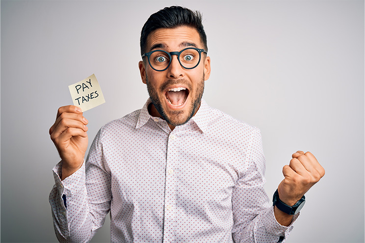 Excited man with a sticky note that says "Pay Taxes."